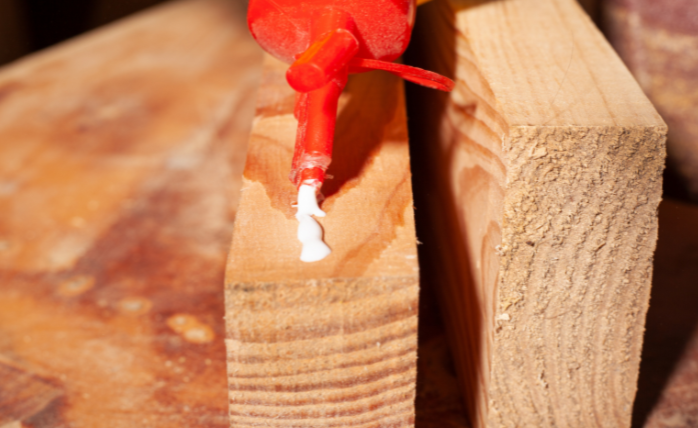 Glue bottle applying glue to wood plank